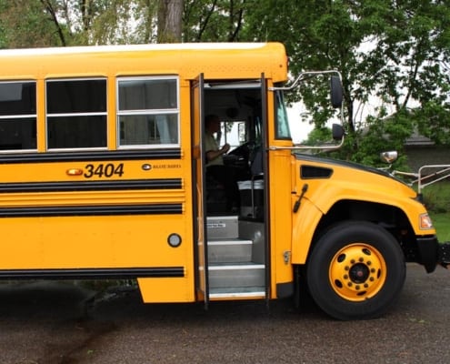 Side view of school bus showing stairs and driver