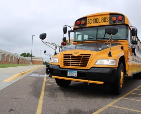 Front view of yellow school bus parked in front of school building