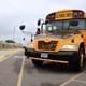 Front view of yellow school bus parked in front of school building