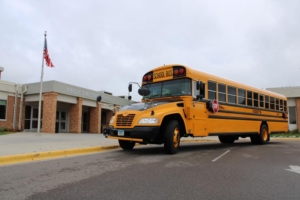 Side view of yellow school bus parked in front of school building