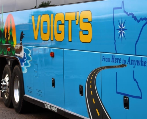 Close up of the side of a light blue Voigt bus featuring a loon, Minnesota state outline, and other Minnesota elements