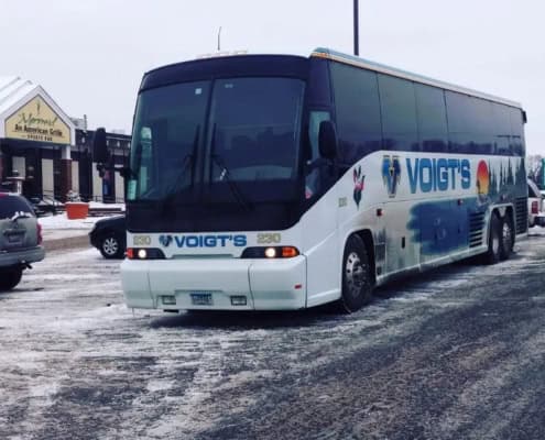 A charter bus parked in a Minnesota parking lot covered in snow and slush.