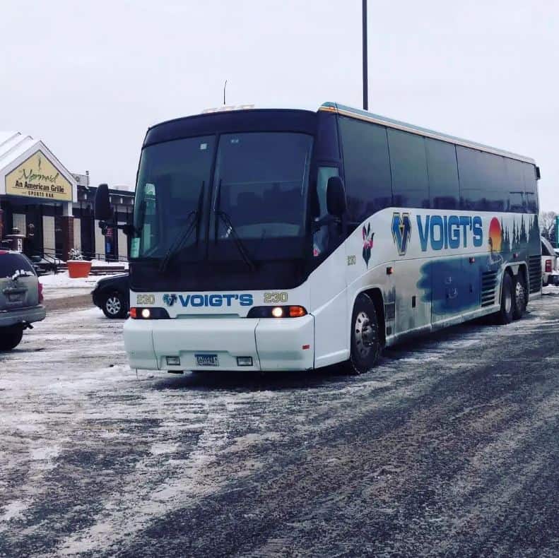 A charter bus parked in a Minnesota parking lot covered in snow and slush.
