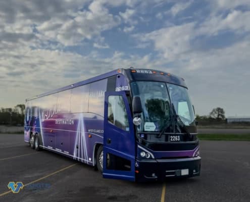 A purple coach bus is parked in a parking lot with its door open.