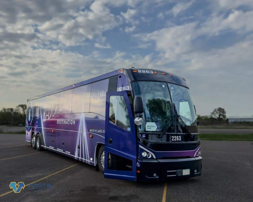 A purple coach bus is parked in a parking lot with its door open.