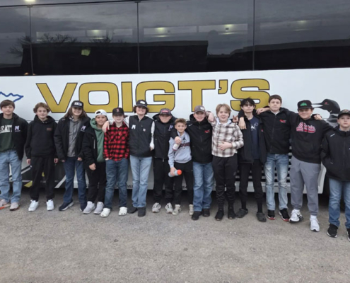 A group of children standing in front of a charter bus.