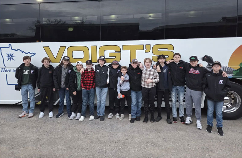 A group of children standing in front of a charter bus.