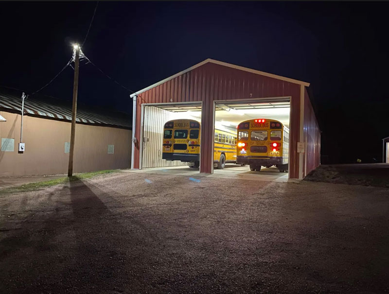 Two school buses are parked in a garage.