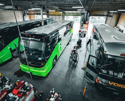 Three buses are sitting in a bus repair garage.