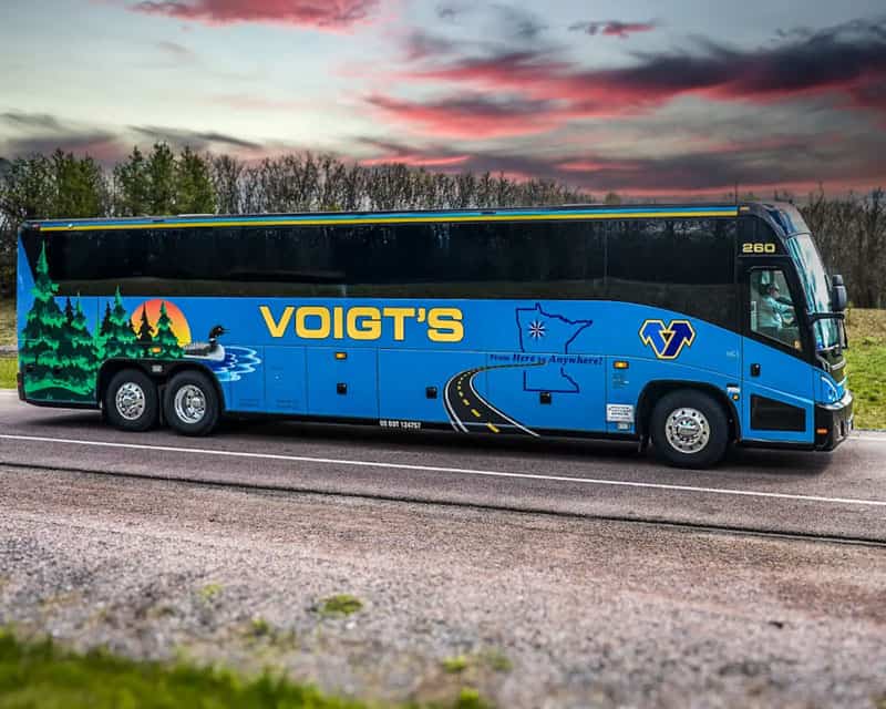 charter-booking A Voigt’s charter bus on the road in front of a beautiful countryside sunset.