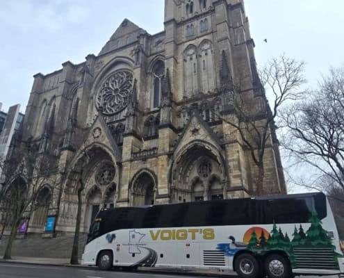 A Voigt’s coach bus parked in front of a historic church.