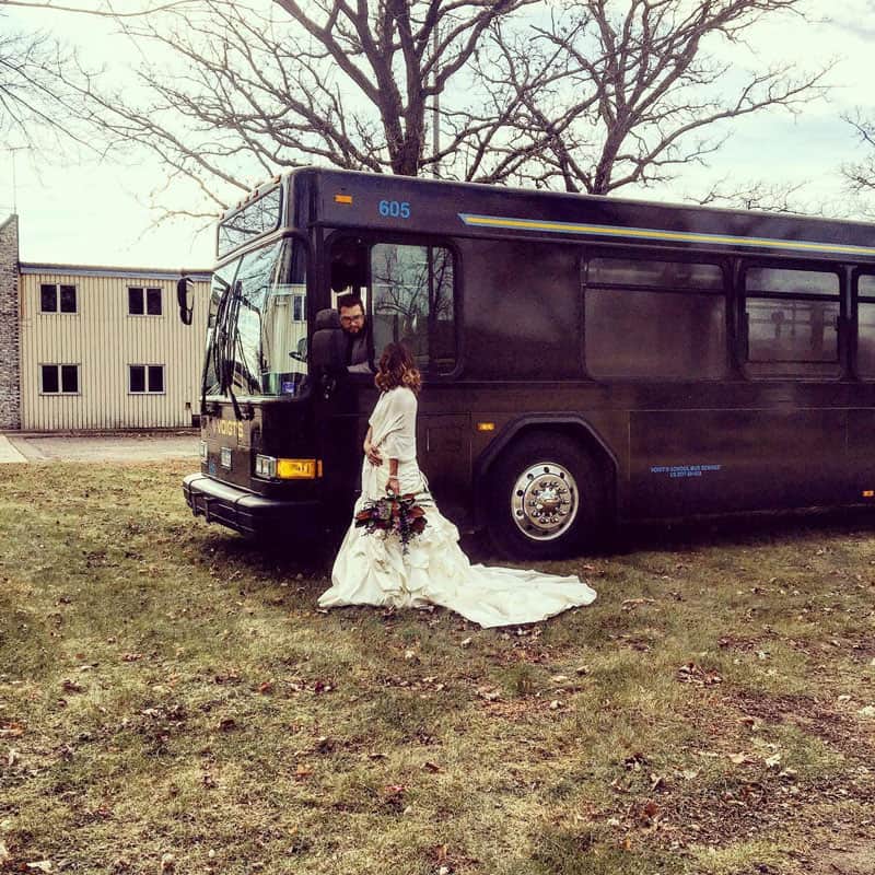 wedding-transport A woman in a wedding dress standing outside a charter bus.