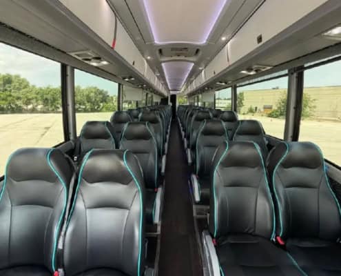 The inside of a large coach bus with black bucket seats for passengers.