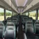 The inside of a large coach bus with black bucket seats for passengers.