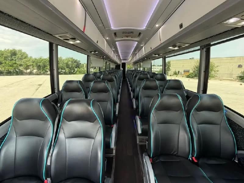 The inside of a large coach bus with black bucket seats for passengers.