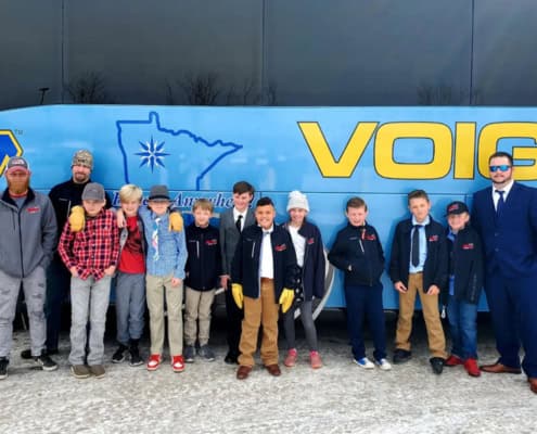 A youth hockey team posing in front of a Voigt’s charter bus.