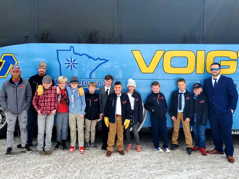 A youth hockey team posing in front of a Voigt’s charter bus.